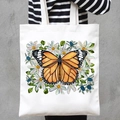 White canvas tote bag featuring orange butterfly and daisy print, hand-held by model - Daisy Butterfly (STD707-D)