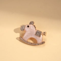 Close-up of pink enamel rocking horse brooch with white rhinestones on beige leather - Pink (Pearl Luster)