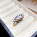 Macro shot of silver wheat leaf ring with cubic zirconia and pearls on a beige box - Silver