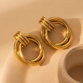 Macro detail of three-ring interlocking golden earrings on textured ceramic surface - Gold Triple Interlocking Hoops (BJGE0702)