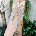 Detail of silver butterfly suncatcher with crystal beads and moon pendant held by hand - Amazonite