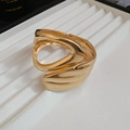 Gros plan d'un bracelet ajouré doré irrégulier sur une plateforme texturée - Bracelet jonc ouvert large évidé irrégulier (Or)
