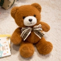Cute dark brown teddy bear plush with striped bow sitting on soft cream rug - Brown Bowtie Style