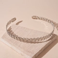 Detailed view of silver wave woven metal collar necklace on a textured stone surface - Silver