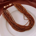 Detail view of multi-strand beaded necklace with gold clasp on white ceramic plate - 25# Necklace-Gold-Brown Multi-strand