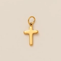 Close-up of polished gold-plated stainless steel cross pendant on beige background - Cross