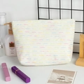 Detail van witte geweven make-uptas met gekleurde stipstrepen en getextureerde afwerking - Wit