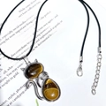 Detailed view of silver cat pendant with tiger eye stone on black leather cord - Tiger's Eye