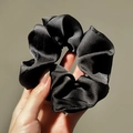 Close-up of black glossy satin scrunchie showing smooth silk-like texture and rich folds - Bright Black