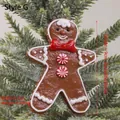 Gingerbread man Christmas ornament with red bow tie and candy cane buttons on tree - Gingerbread Man with Lollipop Style G