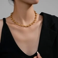 Gold PVD coated stainless steel knot chain necklace worn by a model in a black blazer - Gold Knot U-Shape Link Chain