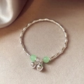 Bamboo style silver bracelet featuring light green beads and delicate bell pendants - Silver-Green