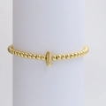 Golden beaded stretch bracelet with high-polish cylindrical charm on a white stand - Gold I
