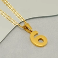 Makroaufnahme einer goldfarbenen Zahl 6 Anhängerkette auf reflektierendem Grund - Nummer 6 (Mit Kreuzkette)