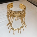 Gros plan d'un bracelet manchette doré avec des franges de chaînes et pendentifs feuilles - Bracelet de Bras à Franges de Plumes Creuses / Doré