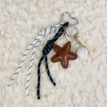 Detail of keychain featuring brown leather star, baseball charms and woven strap - Charm / Baseball Brown Star
