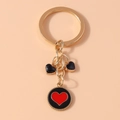 Detail of gold keychain with black and red heart charms and enamel round pendant - Black Red