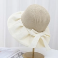 Close-up of elegant straw weave sun hat with cream fabric brim and bow detail - Off White