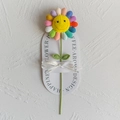 Handmade crochet sunflower with colorful petals and smiling face on card backing - Rainbow Sunflower