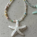Macro detail of iridescent resin starfish pendant and colorful handmade beads - Colorful