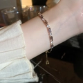 Detail eines eleganten Goldarmbands mit lila Zirkoniasteinen am Handgelenk der Frau - Gold Violett Rechteck