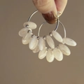 Detail of hand holding silver flower pearl hoop earrings with oval shell beads - 1# Silver Earring Post-White (Shell-like Hoop)