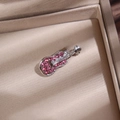 Détail d'une broche guitare argentée avec strass roses dans un écrin à bijoux beige - Violon / Argent avec zircon rose