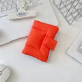 Close-up of orange quilted fabric notebook cover with tie closure on a creative desktop - Orange