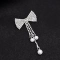 Silver bow brooch with sparkling rhinestones and white pearl tassels on dark background - Solid Bow With Irregular Pearl Tassel
