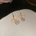 Detalle de pendientes de lazo dorado con corazones de perla y gota de cristal facetado - Gancho de oreja - Dorado