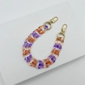 Detail der orange-violetten Acryl-Taschenkette mit goldenen Metall-Karabinern - Transparent Paars Oranje