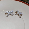 Dettaglio di orecchini a fiocco in argento con zirconi scintillanti su piatto bianco - Coppia d'argento