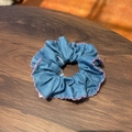 Blue fabric scrunchie with pink wavy embroidered edges on a dark wood background - Blue Denim Scrunchie with Pink Trim