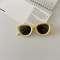 Close-up of kids yellow matte sunglasses with dark lenses on a white notebook - Yellow
