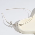 Elegante cerchietto dorato con fiocco di strass su un vassoio di ceramica - Cerchietto con Fiocco