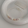 Detail van meerkleurige zoetwaterparelarmband op wit porselein met zilveren accenten - Zoetwaterparel armband / Zilver/Roze