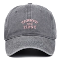 Close-up of pink TANNED and TIPSY embroidery on a washed grey vintage baseball cap - Adjustable / Gray