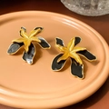 Dettaglio di orecchini a fiore in smalto nero con bordo dorato su piatto di ceramica - 15# Perno in Argento