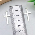 Dettaglio che mostra la dimensione dei ciondoli a croce d'argento con un righello di metallo - Croce Argento Antico 13x27mm