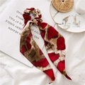Detailed close-up of snake print satin scrunchie with long ribbons on a magazine - Red Snake Pattern