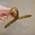 Amber translucent large shark hair claw clip for thick hair shown in a hand-held detail view - Jelly Coffee-15cm (Extended)