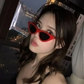 Retro Katzenaugen-Sonnenbrille in Rot mit schwarzen Gläsern an einem Model vor Stadtkulisse - Rot - Graue Gläser