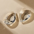 Colgante de cristal tallado en forma de gota sobre fondo beige con reflejos de luz - Cola de fénix