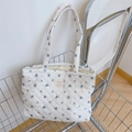 Detail of floral quilted tote bag with diamond stitching and woven label in metal cart - White with Blue Floral