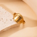 Close-up of a minimalist gold oval-shaped ring displayed on a natural beige stone - Smooth Oval/BJGR0145