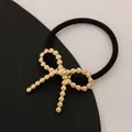 Black elastic hair tie with a polished golden beaded bow accessory for women - Twisted Bow