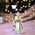 Girl figurine in green vintage dress playing flute on stone under street light - Playing Flute with Light (003-15)