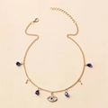 Vergoldete Evil Eye Halskette mit blauen Kristallen und Tropfenanhängern auf Beige - Blau Kristall Böser Blick / Gold