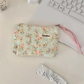 Detailed macro of floral quilted pouch with a pink rope zipper pull on desk - Orange Floral