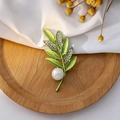 Dettaglio di spilla a foglia verde con strass e perla su una base di legno circolare - Stile Foglia di Strass (Z270)